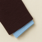 Close-up of a folded brown fabric with blue striped lining on a beige background
