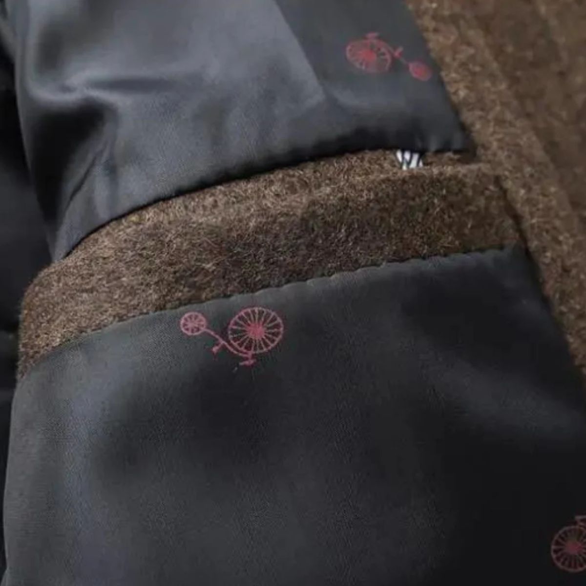 Close-up of a dark fabric with pink embroidered bicycle design.